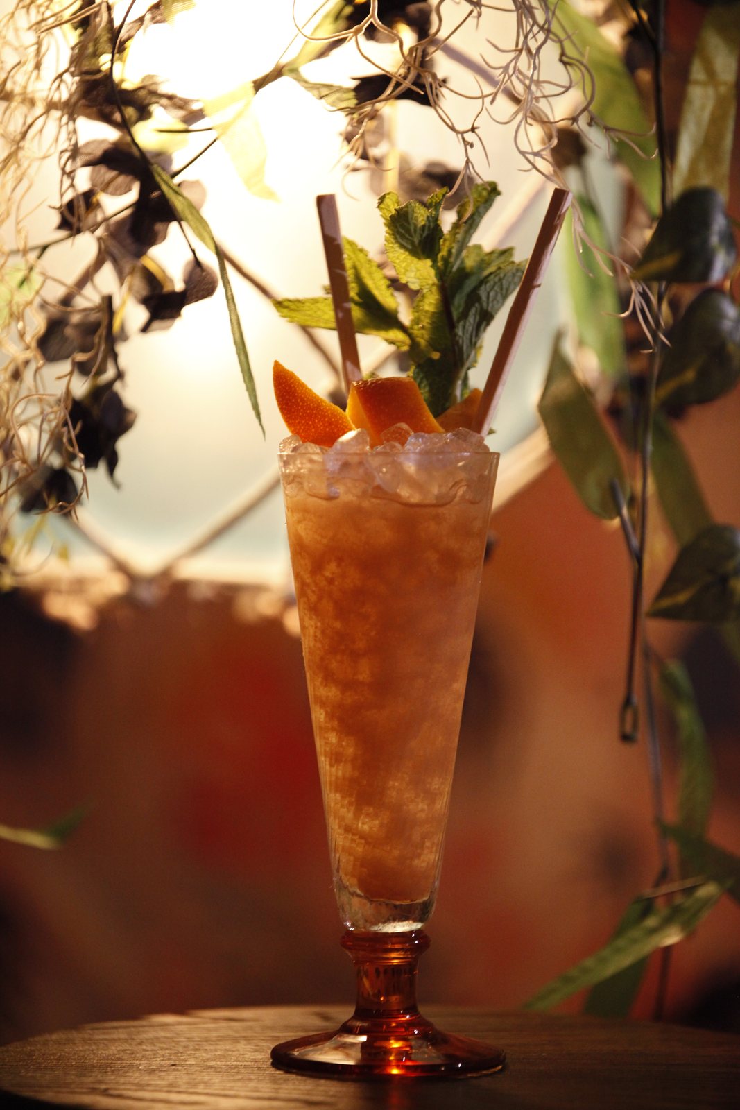Tall swizzle over crushed ice with mint and orange peel